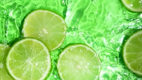 Lime Slices Falling into Water in Slow Motion with Splash, Top View Stock Footage 345657608