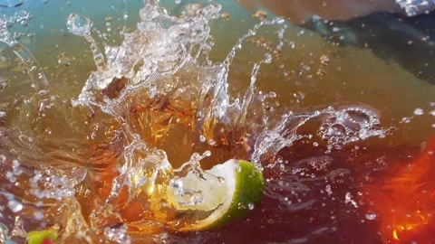 Lime slices splashing into iced tea, creating bubbles and ripples in slow Stock Footage 287697899