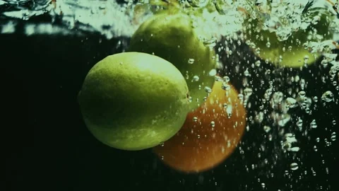 Limes and Oranges Fall and Splash in Water Stock Footage 300892512