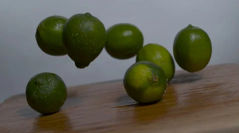 Limes falling in slow motion onto a cutting board - moving barrel roll shot Stock Footage 64682529