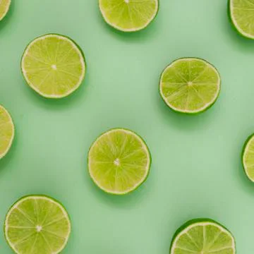 Limes split in half and arranged in a row on a green background Stock Photos