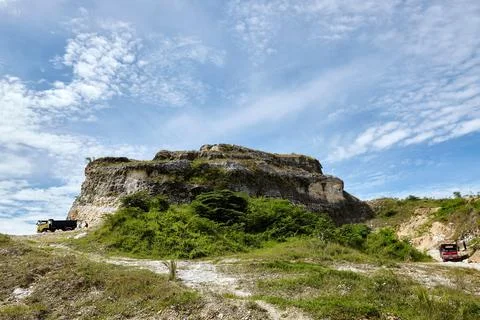 Limestone hill mining with a cloudy blue sky in the background, West Java, Indon Stock Photos
