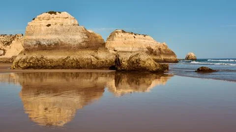 Limestone rocks reflect in the low tide ocean water. Portimao, Portugal Stock Photos