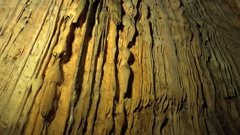 Limestone stalactites hang inside a cave - Erosion Pattern and Illuminated Rock Stock Footage 339644128