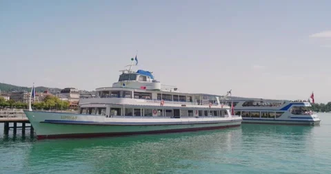 Limmat passenger ferry docked at pier as another boat departs on Lake Zurich Stock Footage 341854018