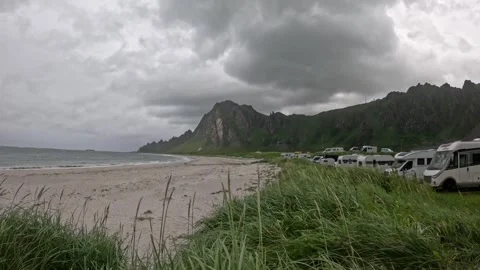 Line of camper vans parked along Bleik beach with dramatic mountains in Norway Vídeos de archivo 343130660
