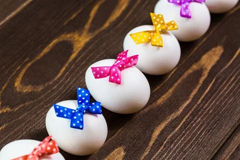 Line of easter eggs with colorful bows are on the wooden background. Stock Photos