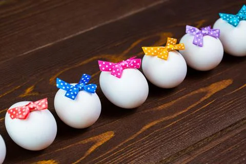 Line of easter eggs with colorful bows are on the wooden background. Stock Photos