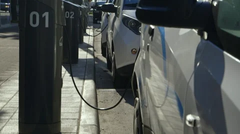 A line of electric cars charging in a downtown city setting Stock Footage