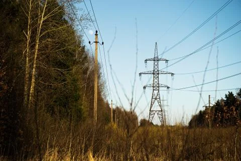 A line of high-voltage pillars through a plowed agricultural field Stock Photos