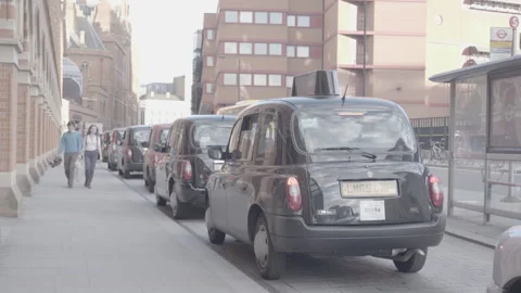 Line of iconic black cabs parked along a London street sidewalk Stock Footage 342564342