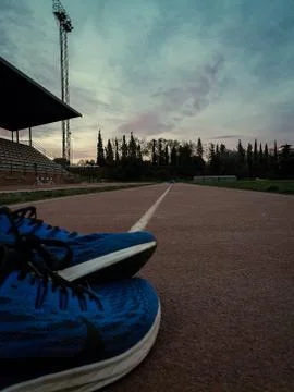 The line of the long jump with a blue shoes over it and the sunset at the end Stock Photos