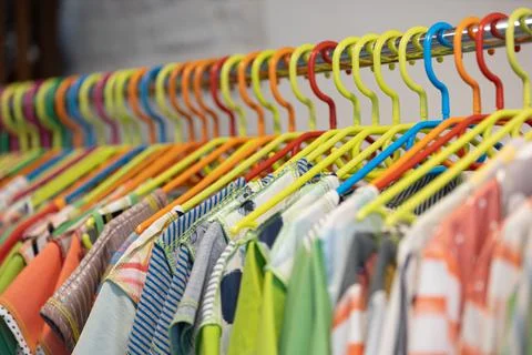 Line of multi colored clothes on plastic hangers in store. Sale Stock-Fotos