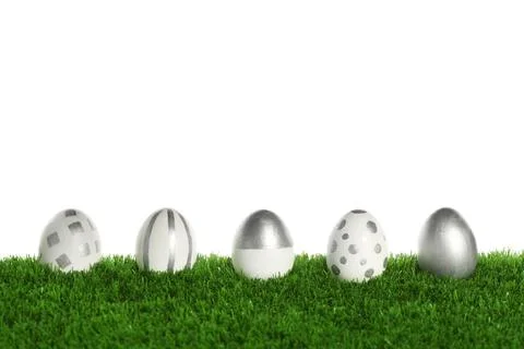 Line of painted Easter eggs on green lawn against white background Stock Photos