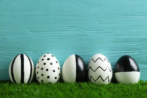 Line of painted Easter eggs on green lawn against wooden background, space fo 스톡 사진