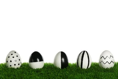 Line of painted Easter eggs on green lawn against white background Foto stock