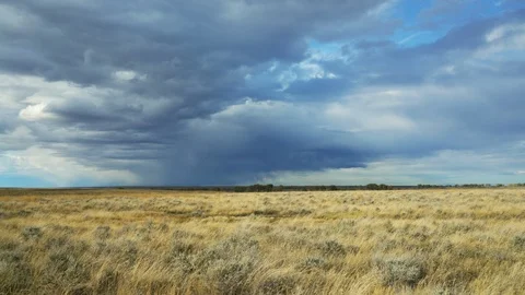 Line of rain clouds sailing across windy sage brush prairie Stock Footage 121344877