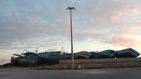 Line row of small wrecked boats ships shipwreck on shore leaning against others Stock Footage 252153424