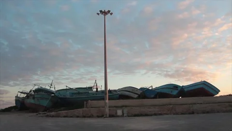 Line row of small wrecked boats ships shipwreck on shore leaning against others Stock Footage 252153428