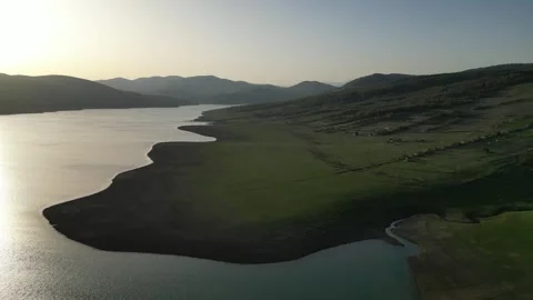 Line of the shore of a mountain lake at sunset, green slope shore, aerial view Stock Footage 274487254