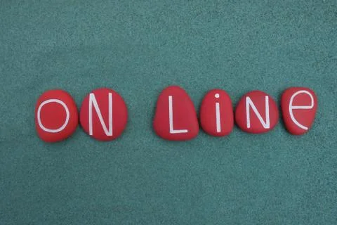 On line text composed with red colored stone letters over green sand Stock Photos