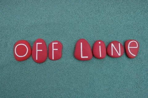 Off line text composed with red colored stone letters over green sand Stock Photos