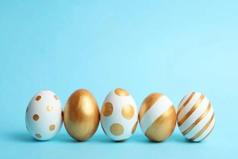 Line of traditional Easter eggs decorated with golden paint on color backgrou Stock Photos