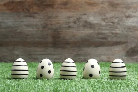 Line of traditional Easter eggs decorated with black paint on green lawn agai Stock Photos