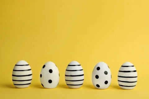 Line of traditional Easter eggs decorated with black paint on color backgroun Stock Photos