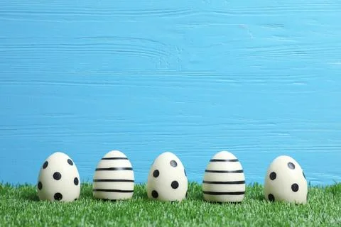 Line of traditional Easter eggs decorated with black paint on green lawn agai Stock Photos
