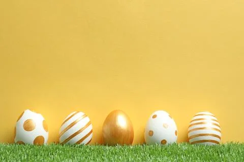 Line of traditional Easter eggs decorated with golden paint on green lawn aga Stock Photos