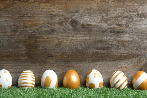 Line of traditional Easter eggs decorated with golden paint on green lawn nea Stock Photos
