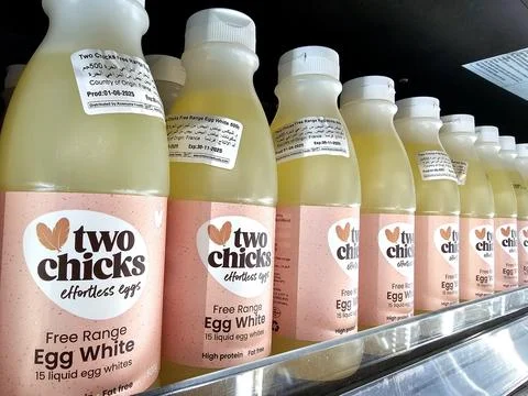 A line of "Two Chicks Free Range Egg White" bottles on a shelf. Stock Photos