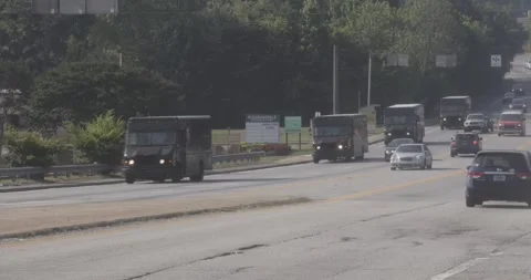 A line of UPS package trucks drive down Atlanta street Stock Footage 245653268