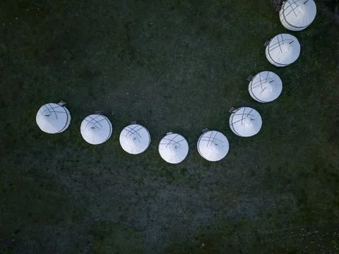 Line of white yurts in a curved pattern on grassy plain, viewed from above, near 写真素材