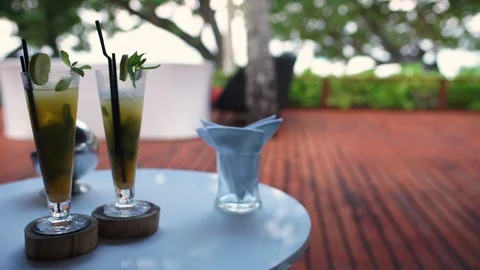 Linear dolly past two fruit cocktail glasses on bar table at outside patio area Stock-Footage 143681920