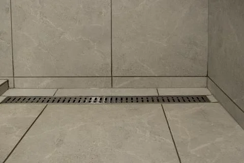 Linear drain in a shower area with gray tiles, a solution for water drainage Stock Photos