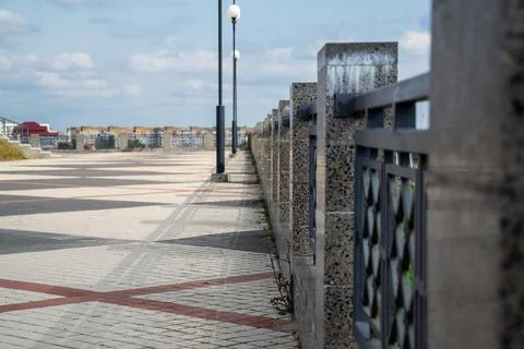 Linear perspective of granite fence posts along patterned paved pedestrian Stock Photos