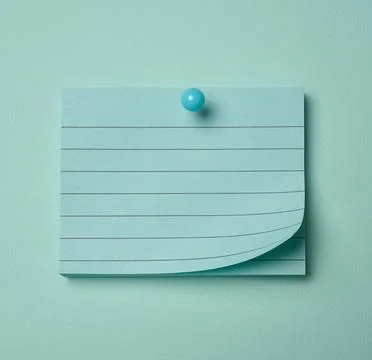 Lined notepad sheet with a curled edge pinned on a blue background. Fotos de archivo