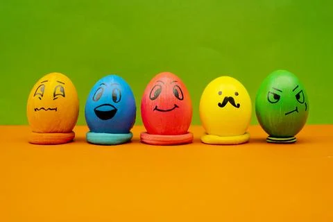 Lined Up Painted Easter Eggs With Expressive Cartoon Faces On Green and Ora.. Stock Photos