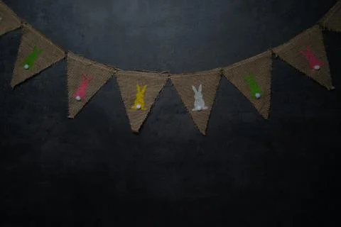 Linen flags with Easter bunnies on a dark stone background Stock Photos