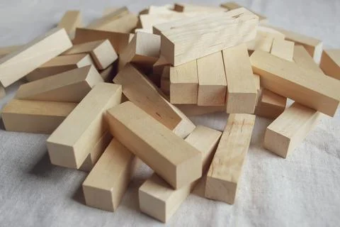 On the linen tablecloth lie elements of the board game Tower. Wooden blocks f Stock Photos