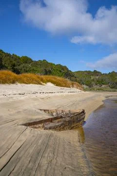 Lines and patterns curving along edge of stream interupted by bow of old wood Stock Photos