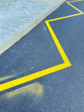 Lines are painted on a paved road showing a zigzag pattern near a sidewalk .. Stock Photos