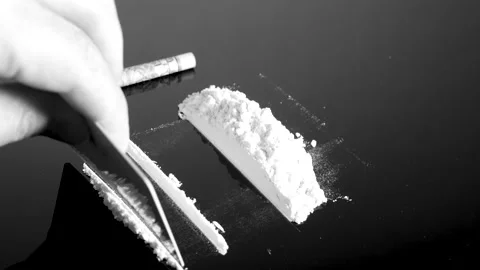Lines of cocaine and a dollar bill. Cocaine lines shots on a black table glass. Video stock 150556523