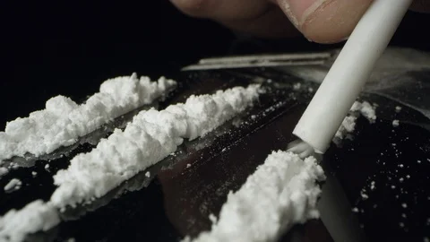 Lines of cocaine being snorted through tube on table top Stock Footage 99781197