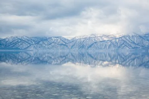 Lines from distant mountain ridges reflected in calm lake water Stock-Fotos