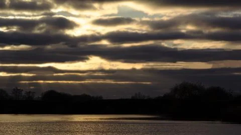 Lines of dramatic clouds at sunset with reflection in the river 写真素材