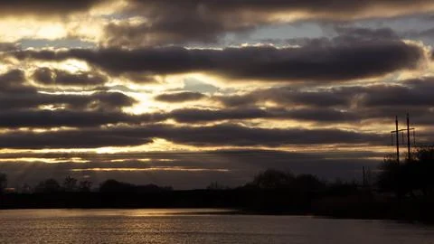 Lines of dramatic clouds at sunset with reflection in the river Stock Photos