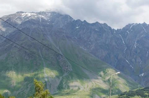 Lines of electrical wires against the backdrop of large green mountain range Stock Photos